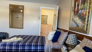 A hotel room with two beds, a sitting area, a bathroom, and a painting on the wall. - Big Bear Lodge (Alpena)