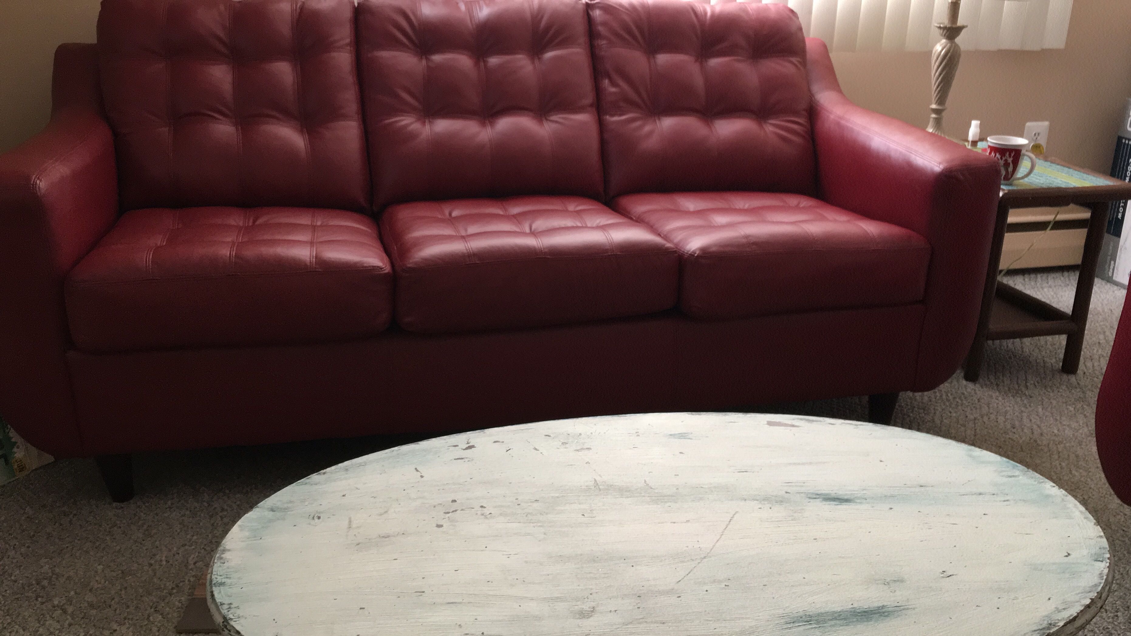 Ein rotes Ledersofa und ein weißer Couchtisch in einem Zimmer.