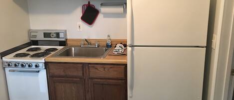 A compact kitchen with a stove, sink, and refrigerator.