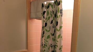 A bathroom with a shower curtain featuring a leaf pattern, a towel rack, and a tiled wall.