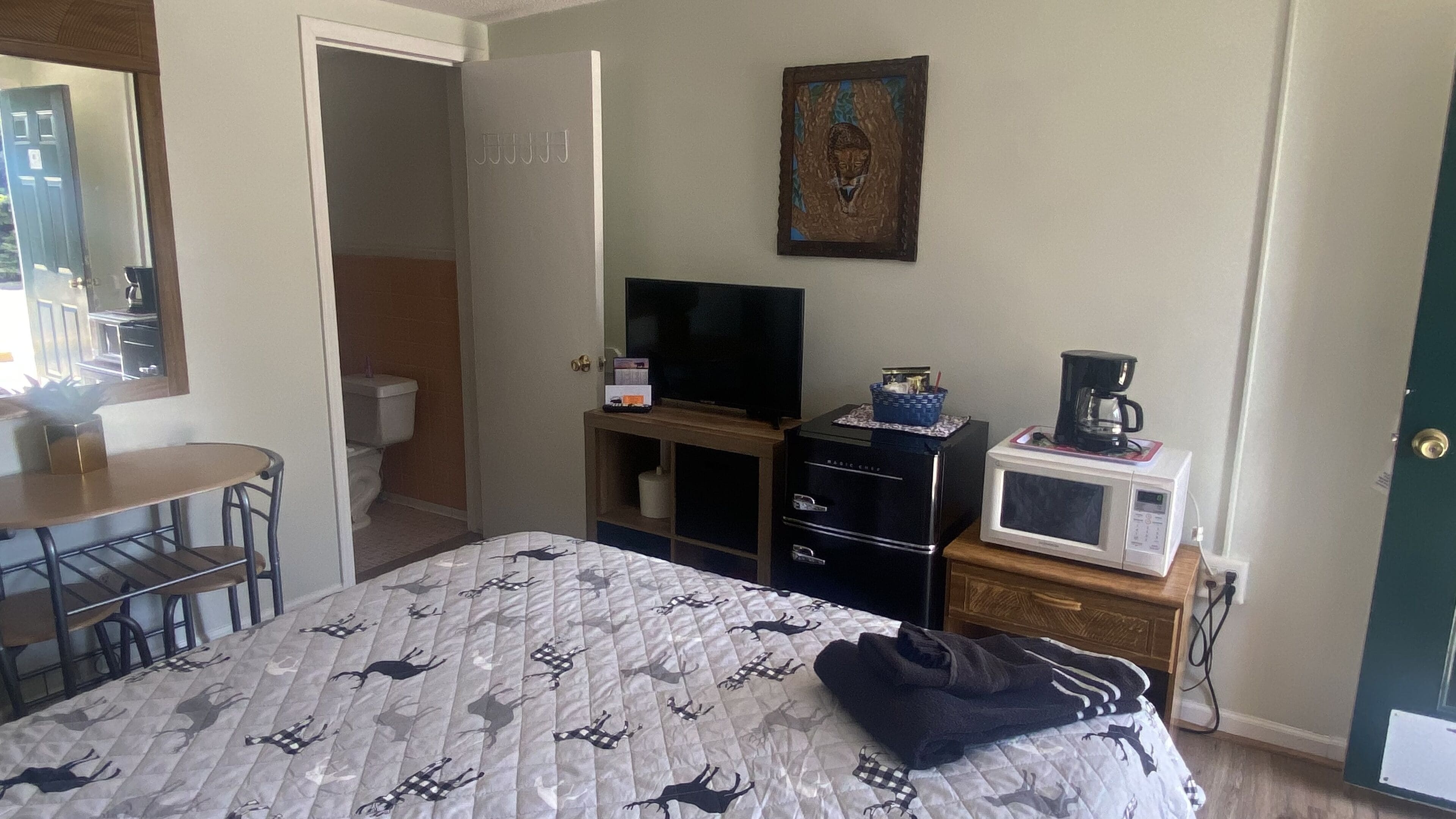 A hotel room with a bed, a desk, a television, a microwave, and a coffee maker.