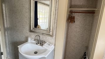 A bathroom with a white sink, a mirror with an ornate frame, and a towel rack.