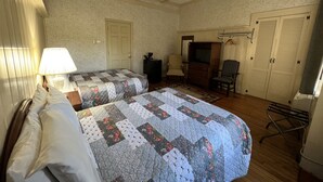 A room with two beds, a television, a chair, and a wardrobe. - School House Inn (North Conway)