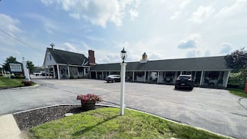 Traditional hotel with a gabled roof and symmetrical facade, set amidst a well-maintained lawn and flower bed.