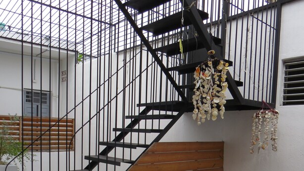 Eine Holztreppe mit einer Bank am Fuß, einem Metallgeländer und einer hängenden Dekoration.