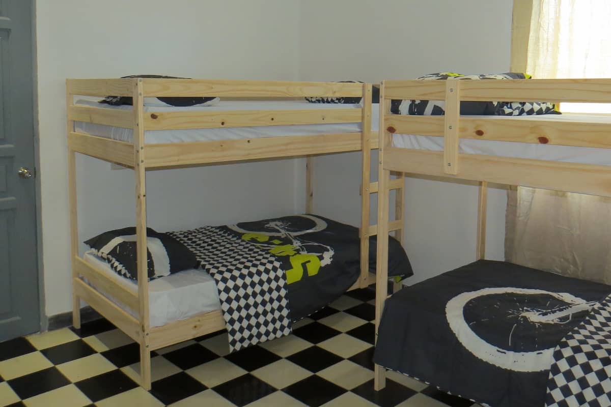 Habitación con literas, suelo a cuadros y ventana con cortinas.
