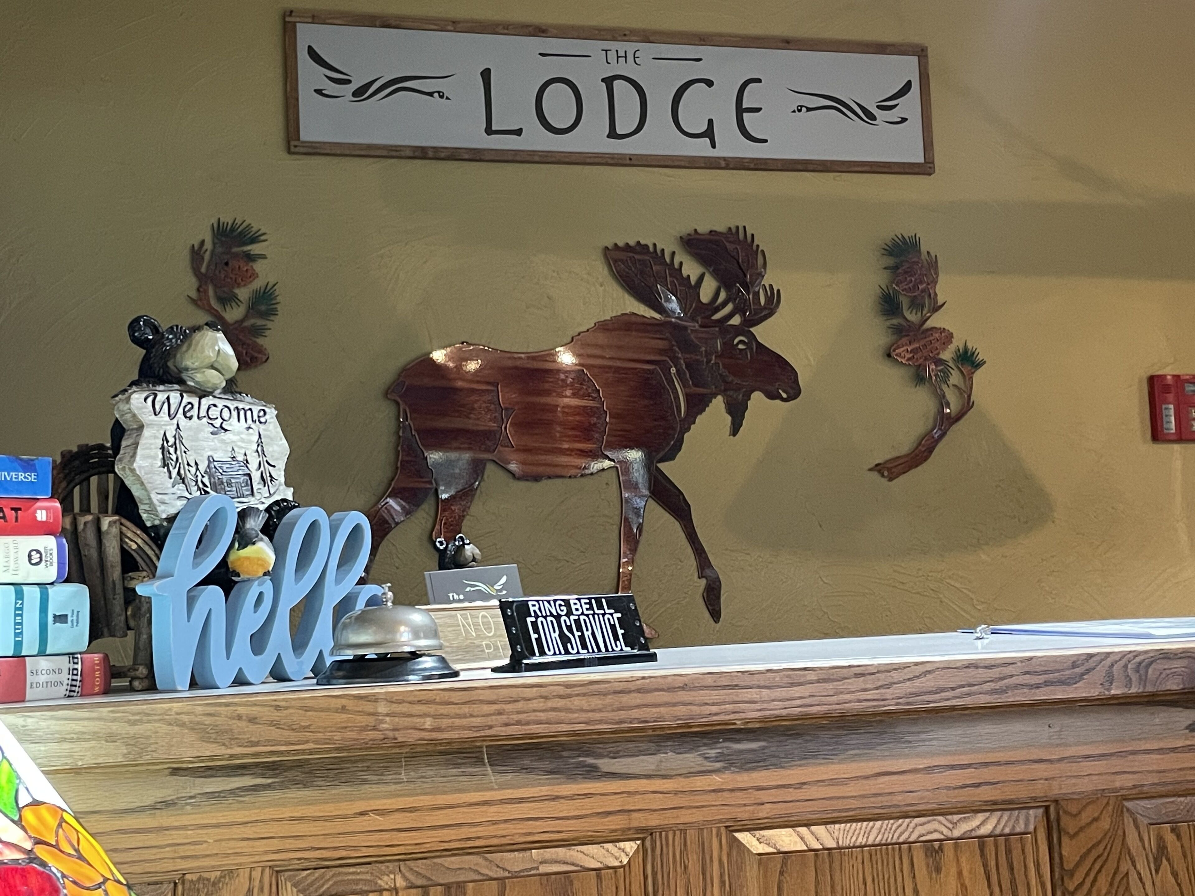 Un comptoir d’accueil avec une enseigne indiquant « The Lodge » et un panneau de bienvenue.
