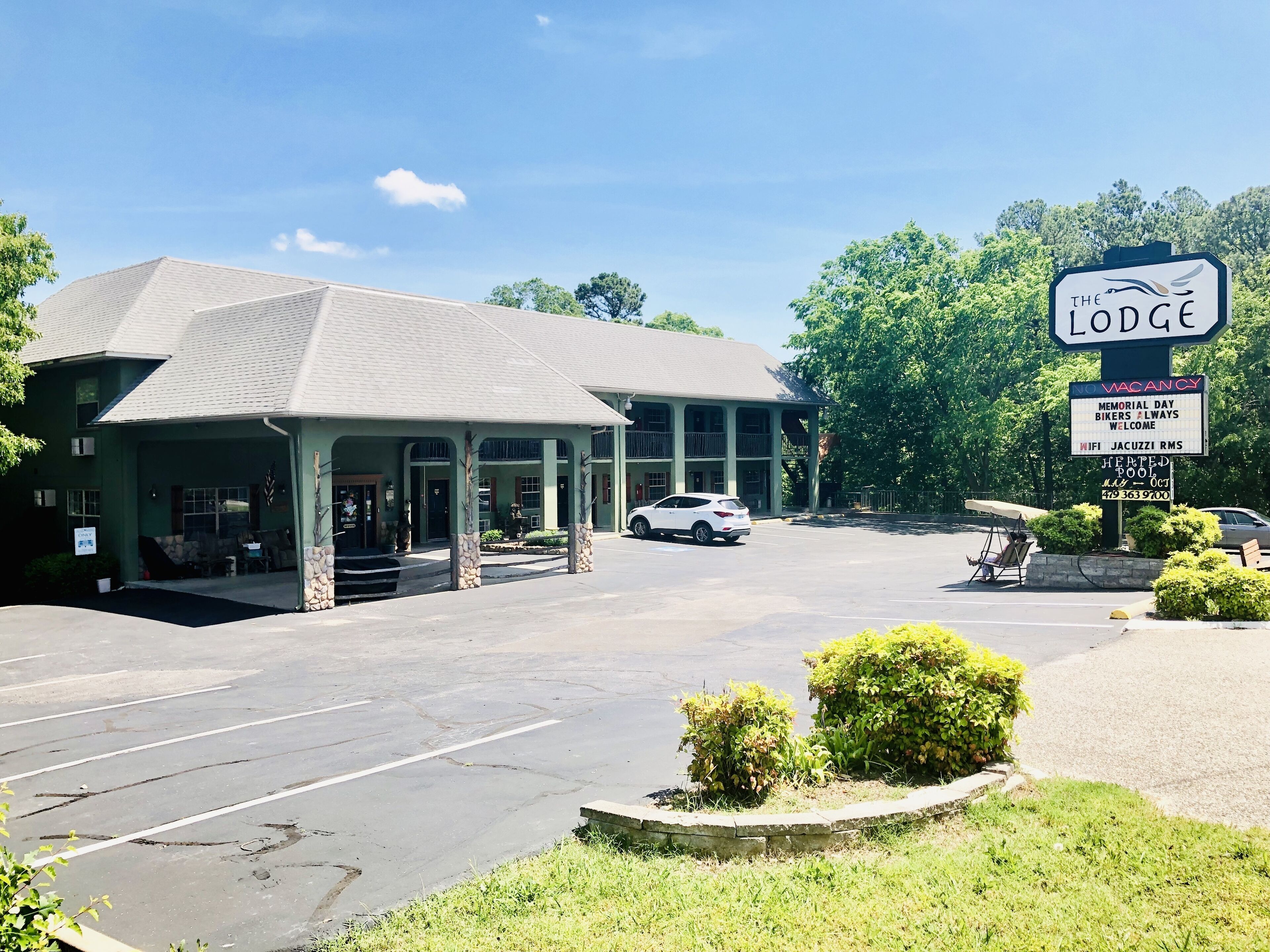 A lodge with a covered entrance, a parking lot, and a signboard advertising amenities like Memorial Day, bikers, and WiFi.