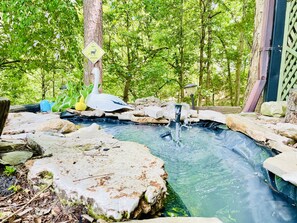 A naturalistic pond with a waterfall, surrounded by rocks and greenery. - The Lodge (Eureka Springs)
