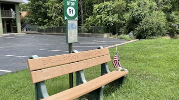 A trolley stop sign with a bench labeled "Eureka Springs' Transit System" and an American flag.
