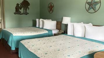 A hotel room with two beds, a nightstand, a lamp, and wall decorations including a star and a silhouette of a cowboy and horse.