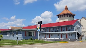 A motel with a red roof, a signboard, and a small tower. - Alpine Motel (Wisconsin Dells)