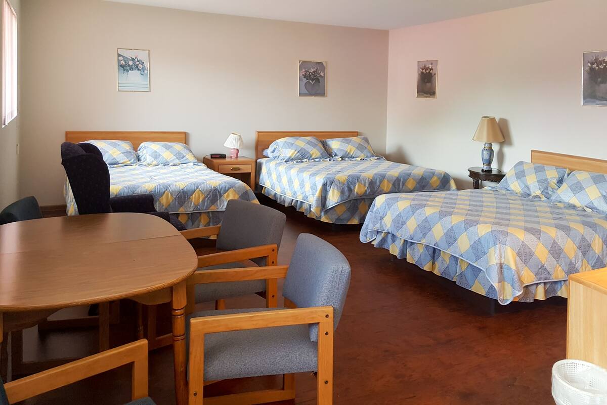 Habitación de hotel con dos camas, una mesa de madera y sillas.