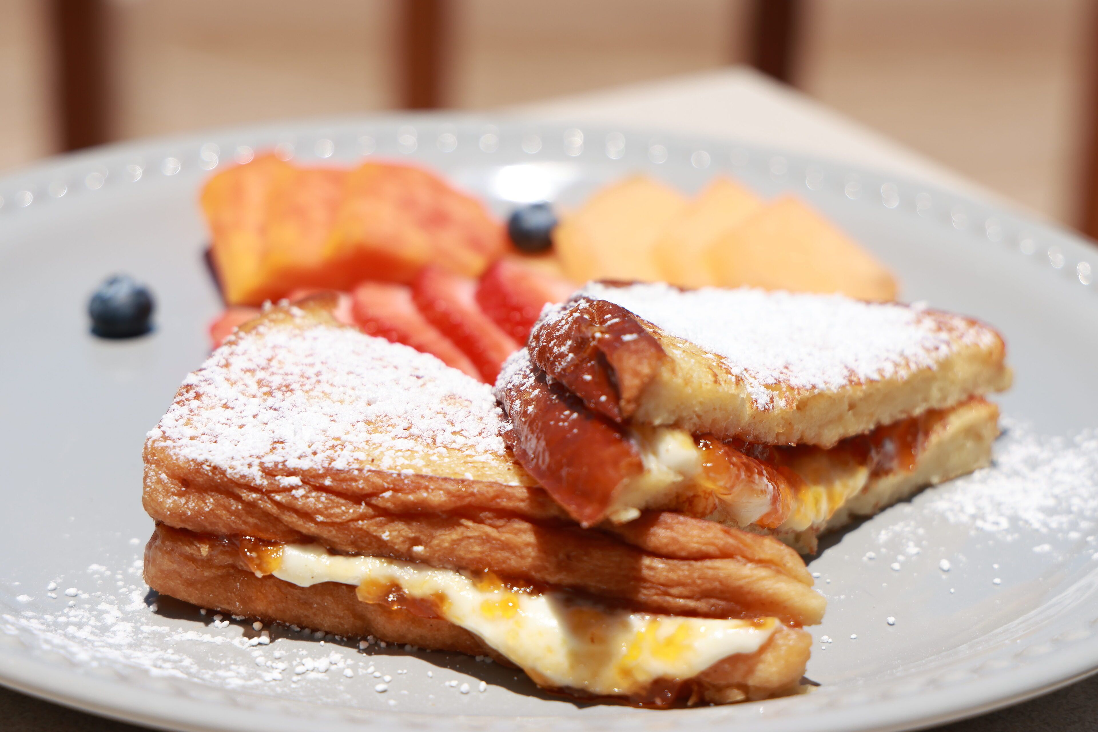 Une assiette avec un sandwich, des fraises et des myrtilles.