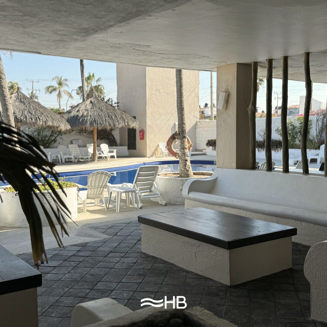 Un área junto a la piscina con sillones de descanso, una piscina pequeña y palmeras.