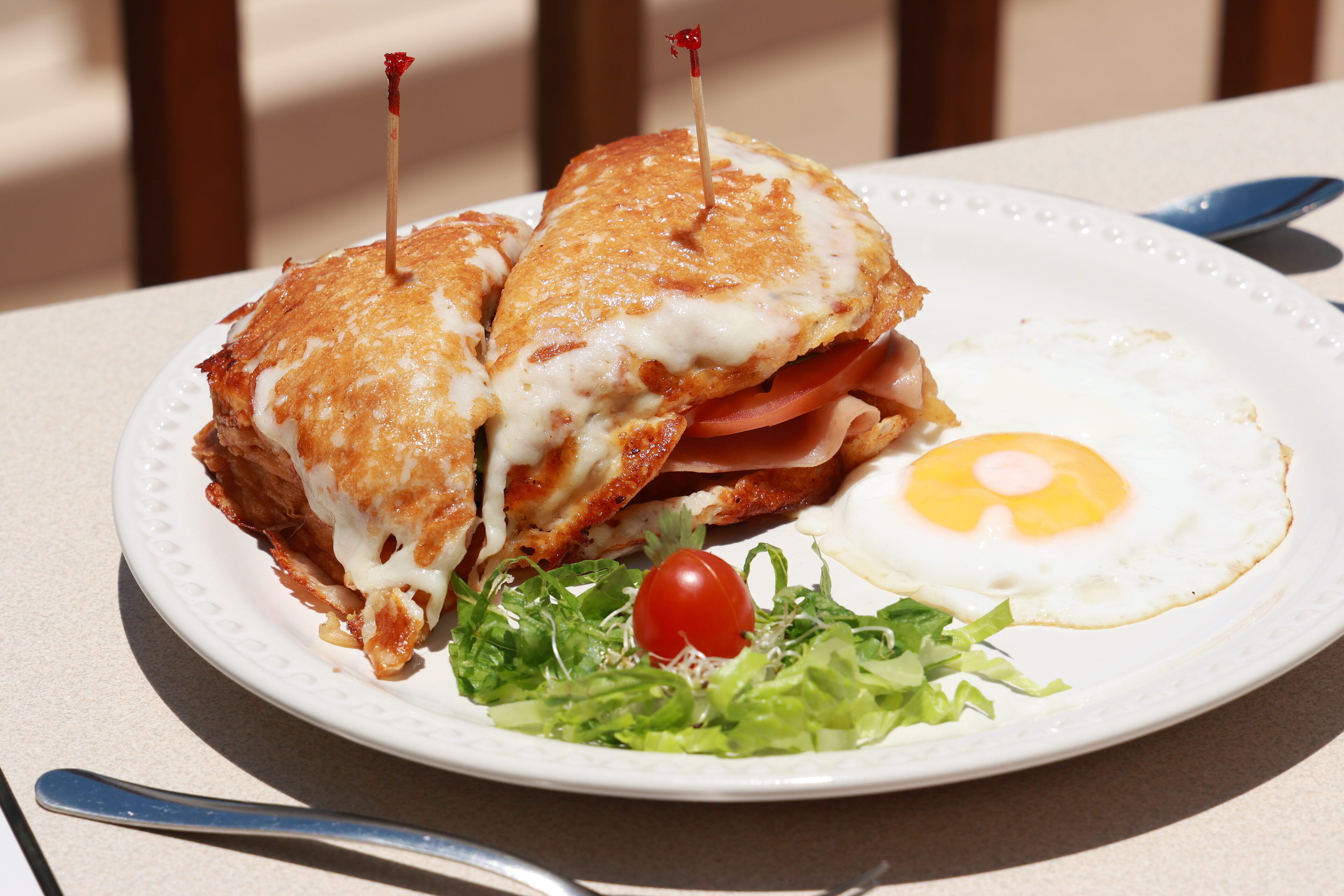 A plate with a sandwich, an egg, and a small salad.