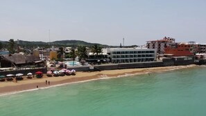 Eine Küstenlandschaft mit Strand, Schwimmbad und mehreren Gebäuden, darunter ein Hotel.