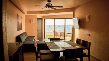 A dining area with a large table, chairs, a sofa, and a ceiling fan.