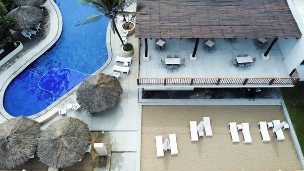 Vista aérea de un resort con piscina, mobiliario exterior y una zona cubierta.