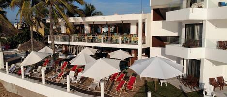 A resort with multiple balconies, sun loungers, and palm trees.