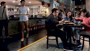 A restaurant with a counter where a server is attending to customers. There are tables with diners, and a sign above the counter indicates the restaurant's name. - Resorts World Genting RW Hotel (Genting Highlands)