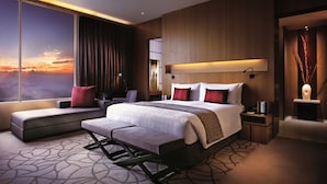 A modern hotel room with a large bed, a seating area, a desk, and a view of the sunset. - Resorts World Genting RW Hotel (Genting Highlands)
