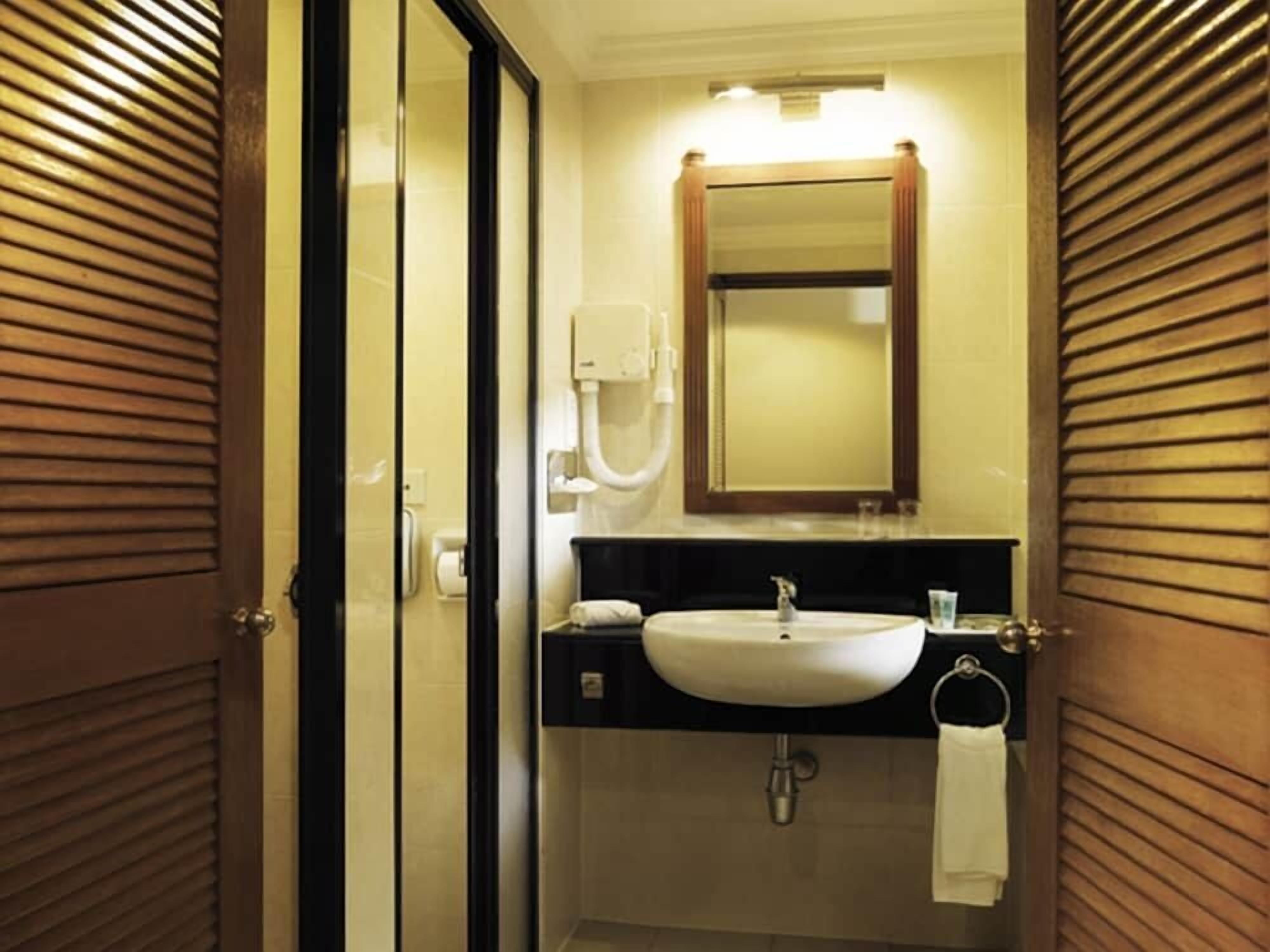 A bathroom with a sink, mirror, towel rack, and a toilet paper holder.