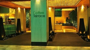 A modern hotel lobby with a central column labeled 'Coffee Terrace,' wooden flooring, and a reception desk. - Resorts World Genting RW Hotel (Genting Highlands)
