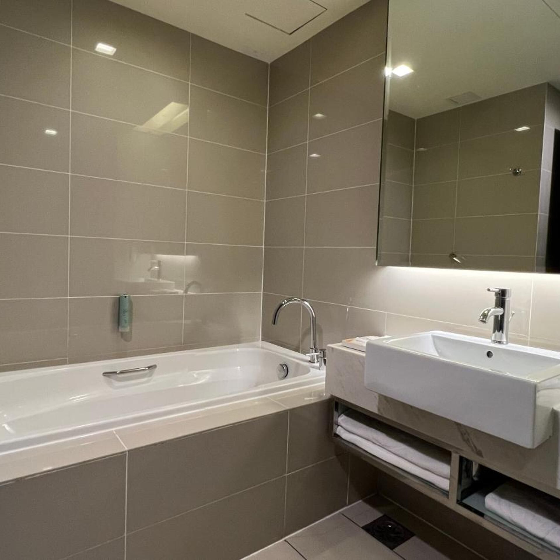 A modern bathroom with a bathtub, a sink, and a mirror.