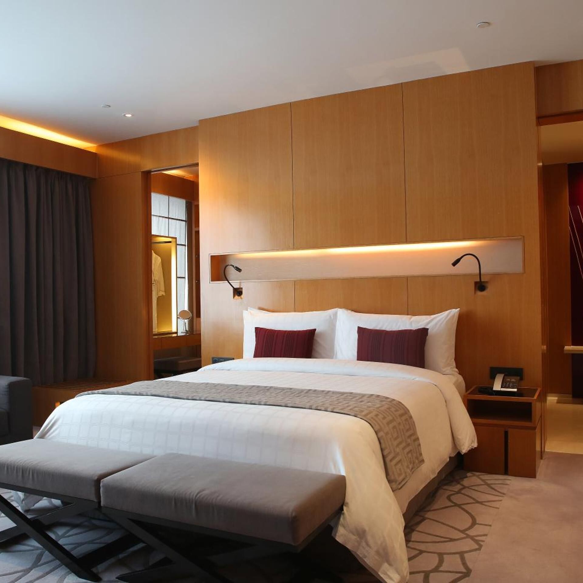 A hotel room with a large bed, bedside tables, a desk, and a chair.