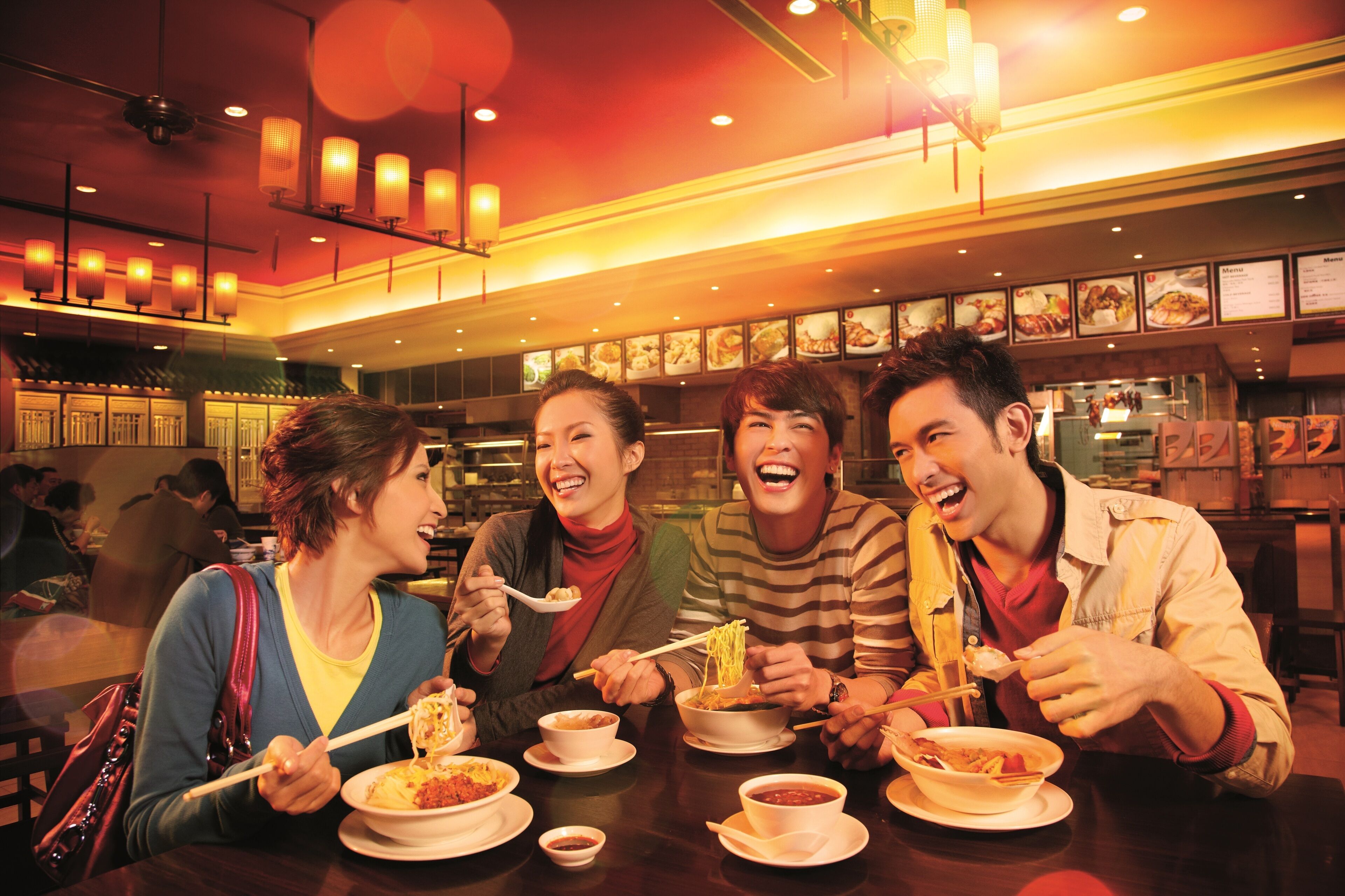 A group of people dining at a restaurant with multiple tables and a variety of dishes.