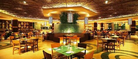 A spacious dining area with multiple tables and chairs, a central seating area, and a unique ceiling design.