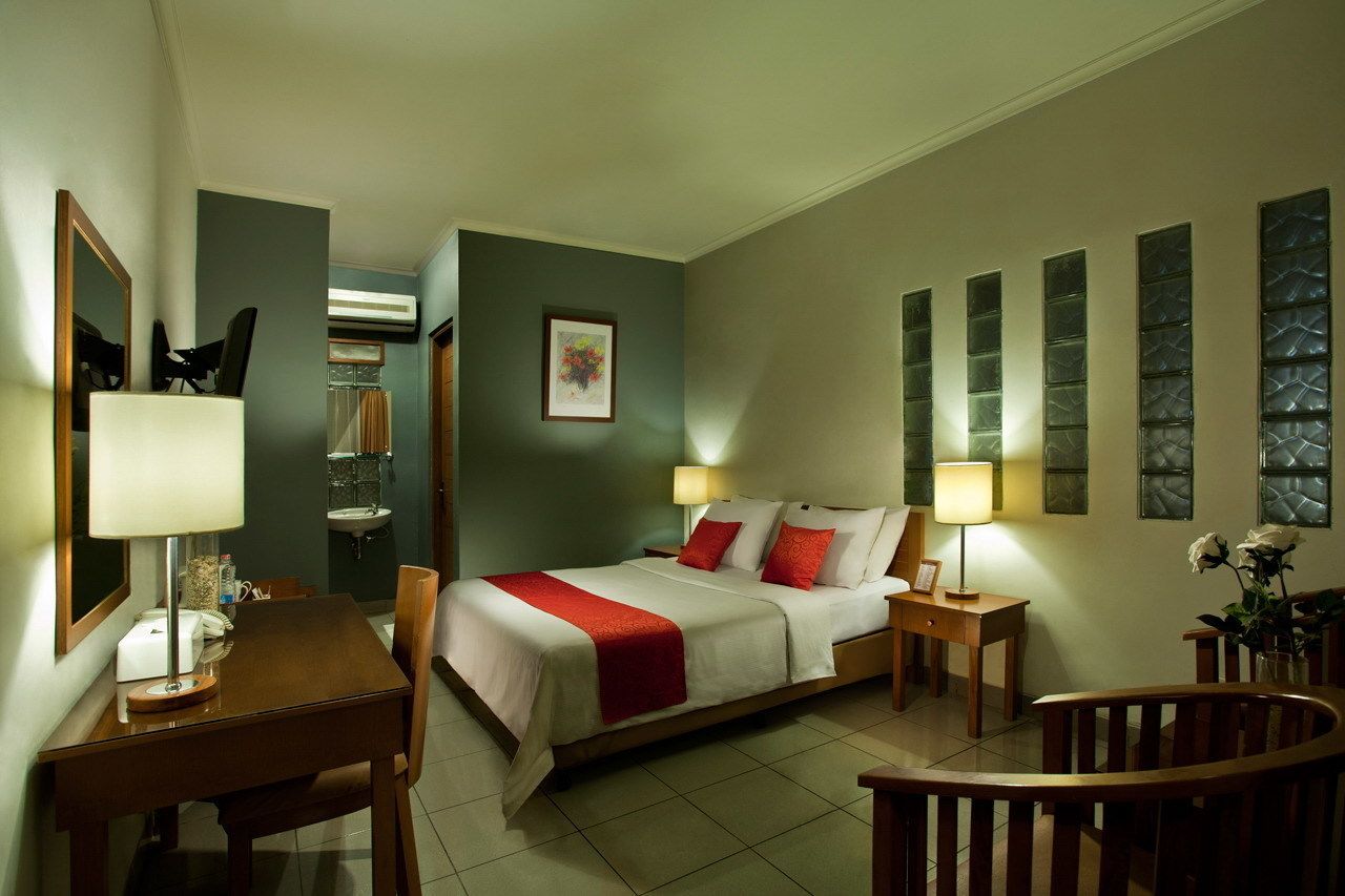 A hotel room with a bed, bedside tables, a desk, and a chair.