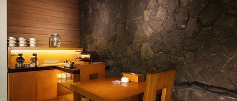 Cocina compacta con armarios de madera, pared de piedra y comedor con mesa y sillas.