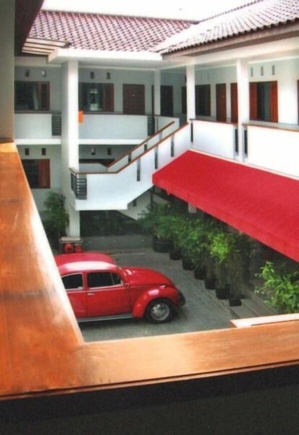 A multi-story building with a red car parked on the ground floor. - Hotel Ilos (Bandung)
