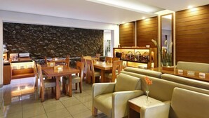 A modern dining area with wooden furniture, a stone wall, and a wooden panel wall. - Hotel Ilos (Bandung)