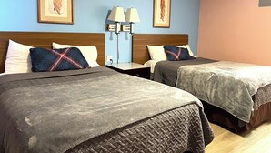 Een hotelkamer met twee bedden, elk met een grijze spreidek en kussens, een nachtkastje met een lamp, en lijstwerken aan de wanden.