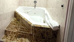 Een badkamer met een vrijstaand bad, een vloer met een marmerpatroon en een handdoek ernaast.