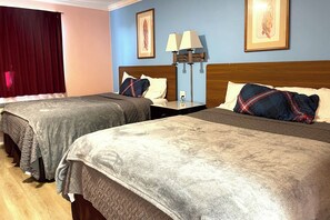 A hotel room with two beds, a nightstand, a lamp, and artwork on the walls. - Travel Inn (Los Angeles)