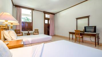 Una habitación de hotel con dos camas, un escritorio con televisor, una lámpara y una silla.