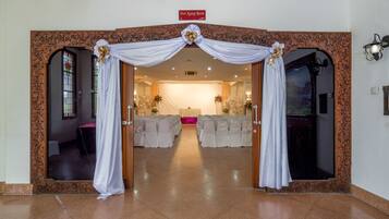 Un arc décoré mène à une pièce aux rideaux blancs, sur laquelle est apposée une enseigne indiquant « Puri Agung Room ».
