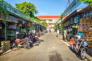 A bustling street market with motorcycles parked on the side and vendors selling goods.