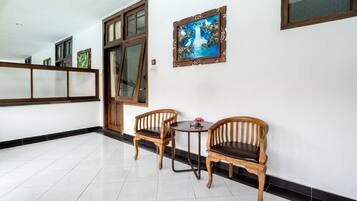 Un pasillo con dos sillas de madera, una mesa pequeña, una puerta y un cuadro enmarcado en la pared.