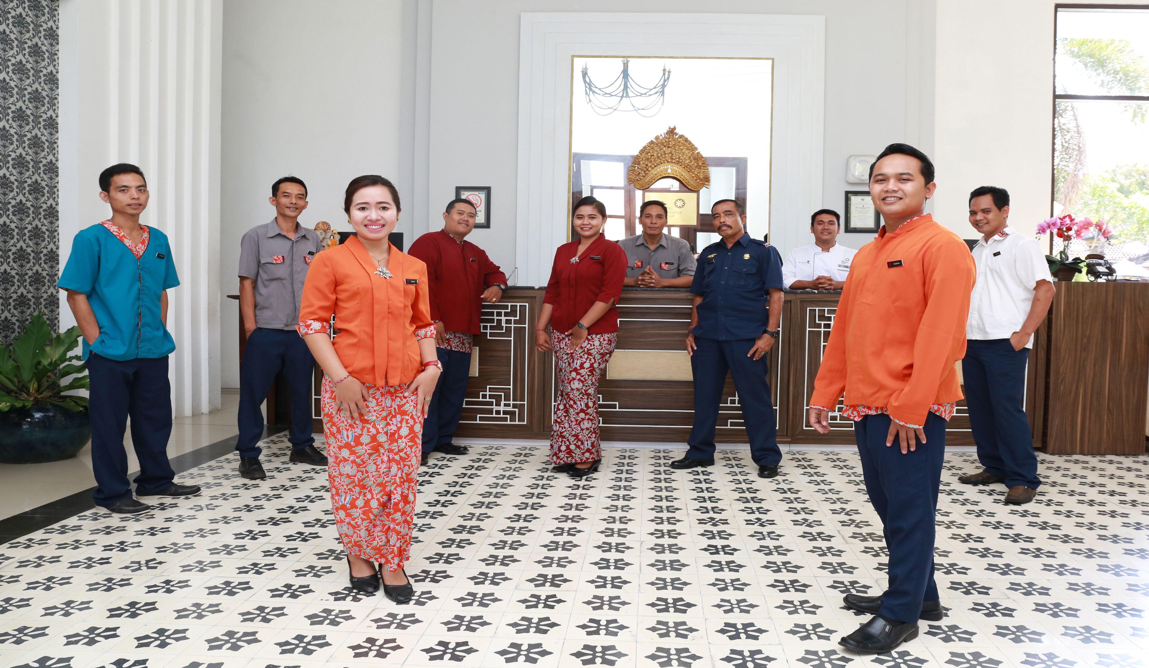 A group of people standing in a room with patterned flooring and a reception desk.