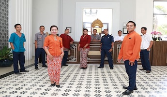 A group of people standing in a room with patterned flooring and a reception desk.