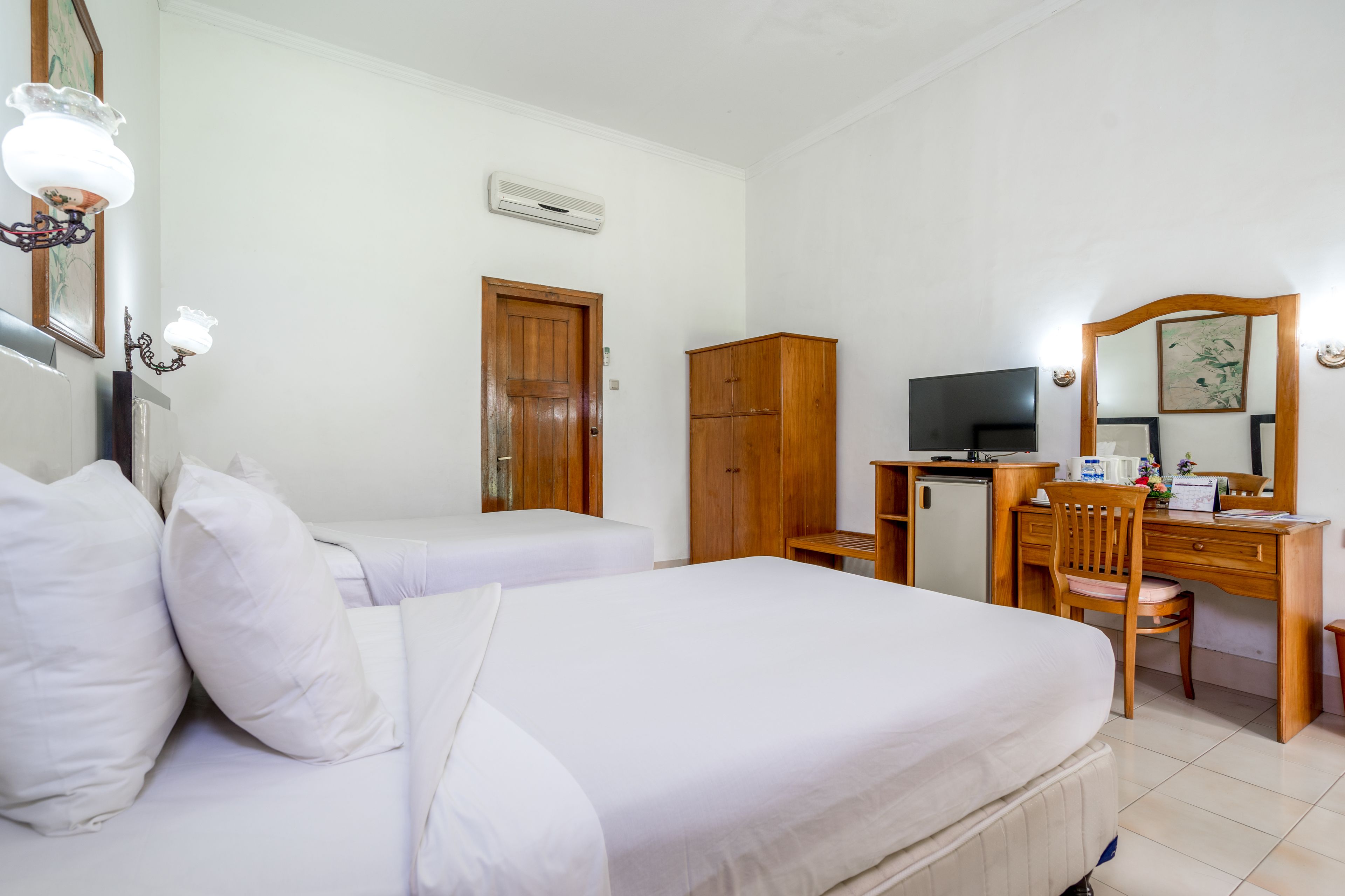 A hotel room with two beds, a desk with a chair, a television, and a wardrobe.