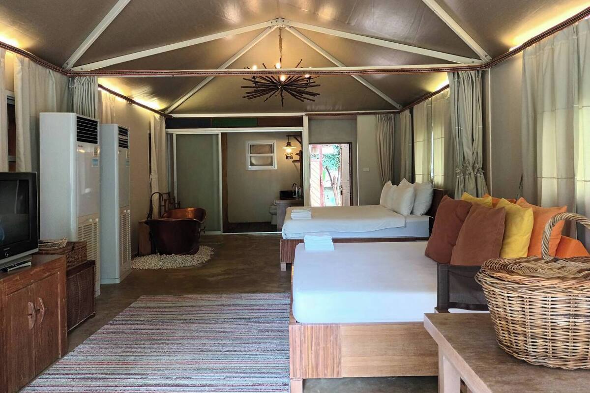 A spacious room with a large bed, a television, and a seating area with a wicker basket.