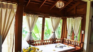 A room with a wooden bench, a bed with a white mattress, and curtains. - Pai Vimaan Resort (Pai)