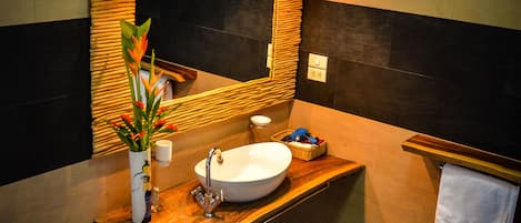 A modern bathroom with a wooden vanity, a large mirror, a white sink, and a toilet.