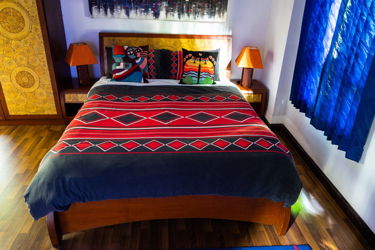 A bed with a patterned bedspread, two bedside lamps, and a headboard with decorative pillows.